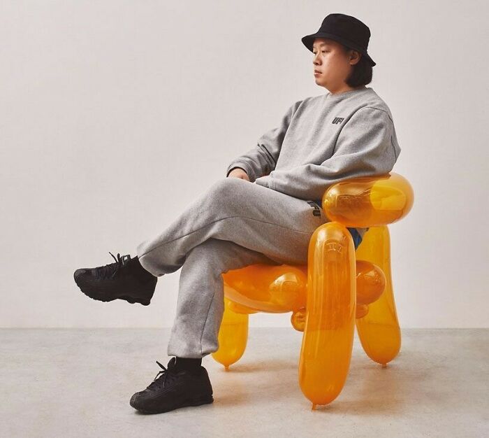 A brilliant design choice: a person sitting on an orange balloon animal chair, creating a playful look.
