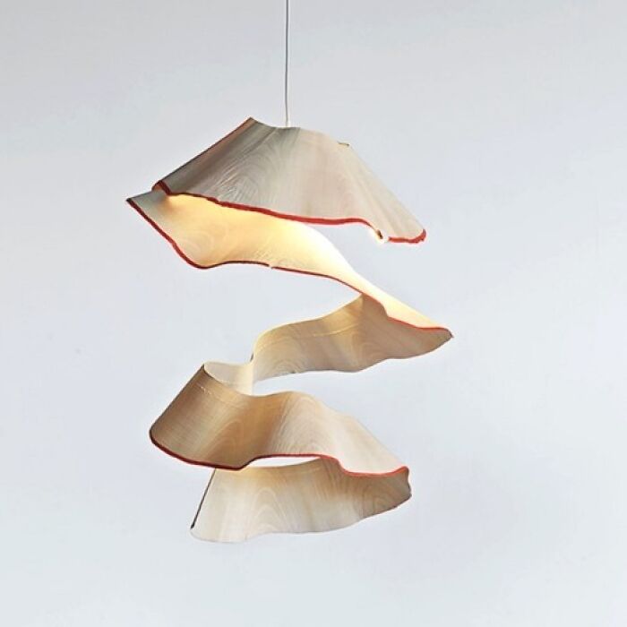 An abstract light fixture with swirling wood and red accents, displaying brilliant design choices.