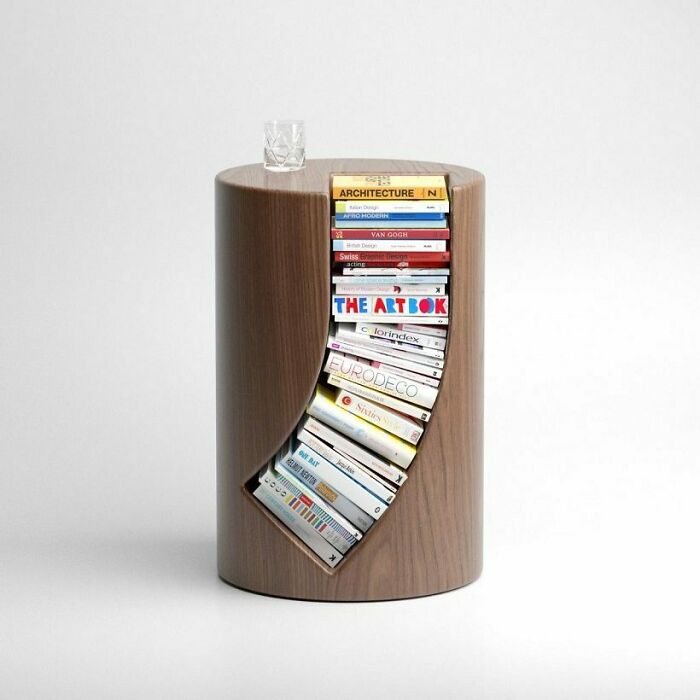 A round wooden side table with a brilliant design choice featuring a curved cutout for books.