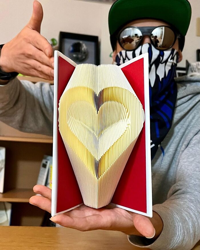 Person holding a book with brilliant design choices, the pages folded into a heart shape.