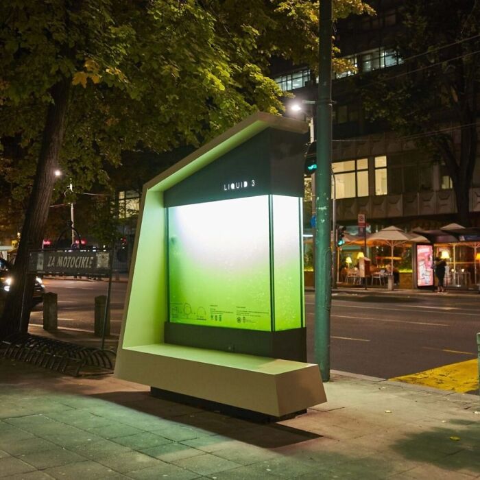 A brilliant design of a modern bus stop with a green-lit panel and a comfortable bench, an example of brilliant public space design choices.