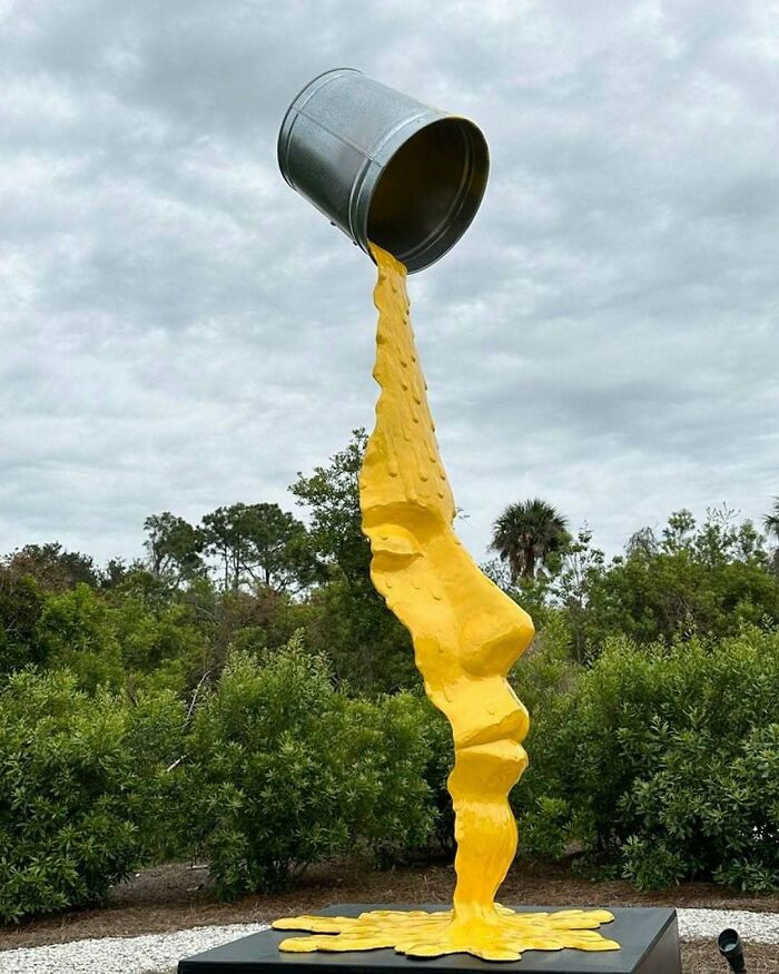A large outdoor sculpture of yellow liquid pouring from a bucket, forming a human profile, a brilliant design choice.