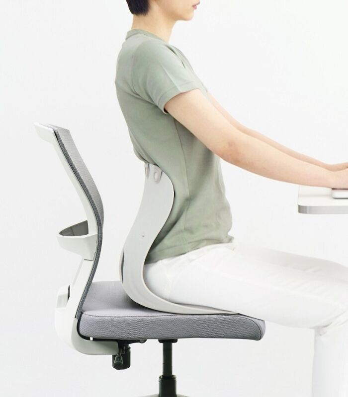 A person sits on an office chair with a brilliant design choice for ergonomic back support.