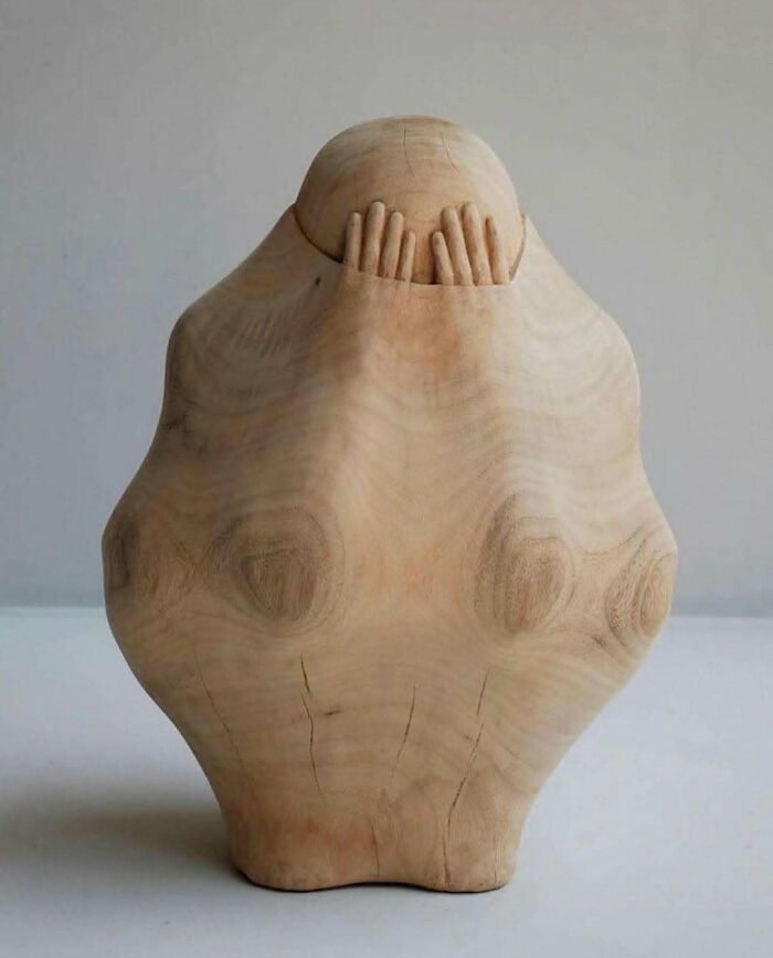 A brilliant design choice in sculpture: a smooth wooden figure with hands emerging from the top, surprising people.