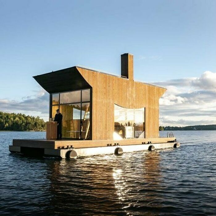 A brilliant design choice for a floating house on a serene lake under a clear sky.