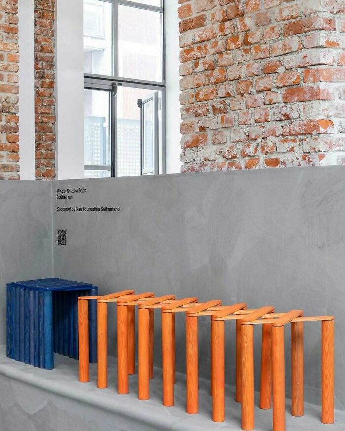 A brilliant design choice: blue and orange wooden benches next to a brick wall and a window, surprising people.