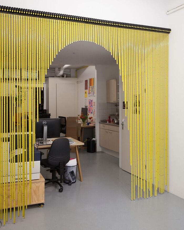 A brilliant design choice: a doorway adorned with a yellow measuring tape curtain, surprising people.