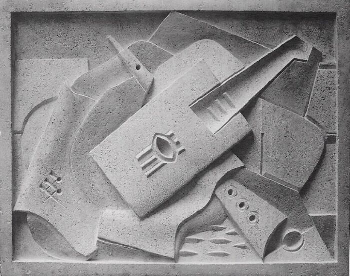 Abstract brilliant design choices in a stone carving, featuring a guitar and other shapes.