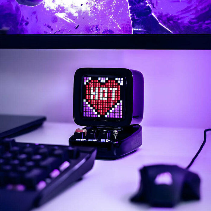 A brilliant design choice: a small pixel art speaker displaying HOT, blending retro aesthetics with modern tech on a desk.