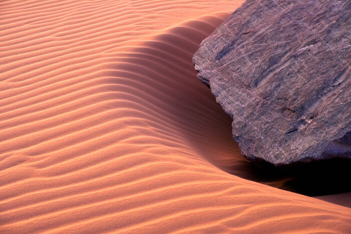Award-winning photographer captures the beauty of nature through extraordinary close-up portraits of a rock on sand dunes.