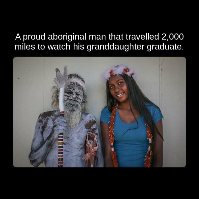 A proud aboriginal man, painted in traditional white body paint, stands beside his smiling granddaughter in graduation attire. Unseen facts.