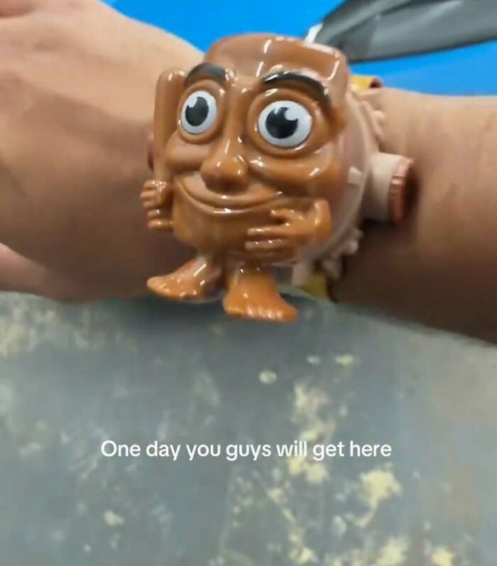 A wrist-worn, brown, character toy with big eyes and a bat, exemplifying unhinged and cringe memes.