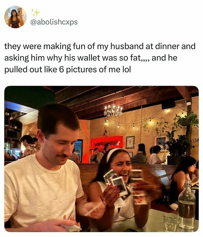 A man and woman laughing as she holds pictures, perfect for a quick laugh from random memes.