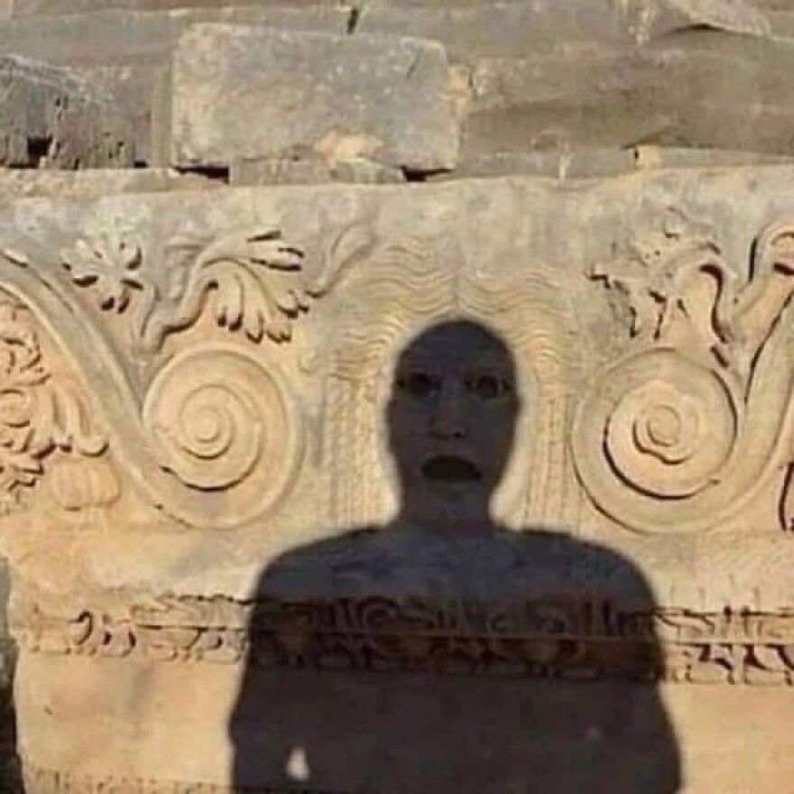 Funny and stupid screenshot of a shadow appearing as a screaming face on ancient ruins, depicting weird people on the internet.