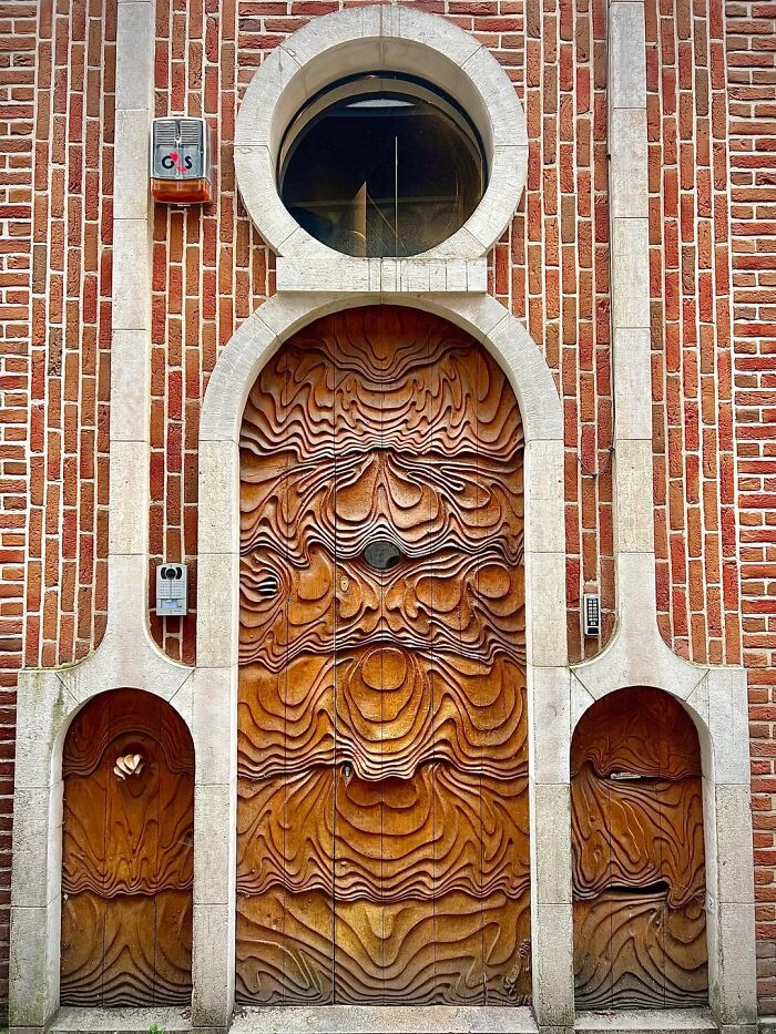A remarkable historic interior with a heavily carved wooden door and two smaller side doors within a red brick facade.