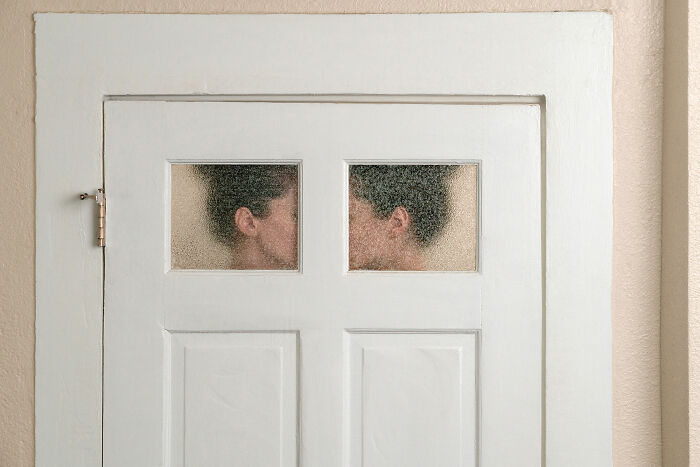 A photographer creates surreal images of a couple kissing through frosted glass panes on a white door.