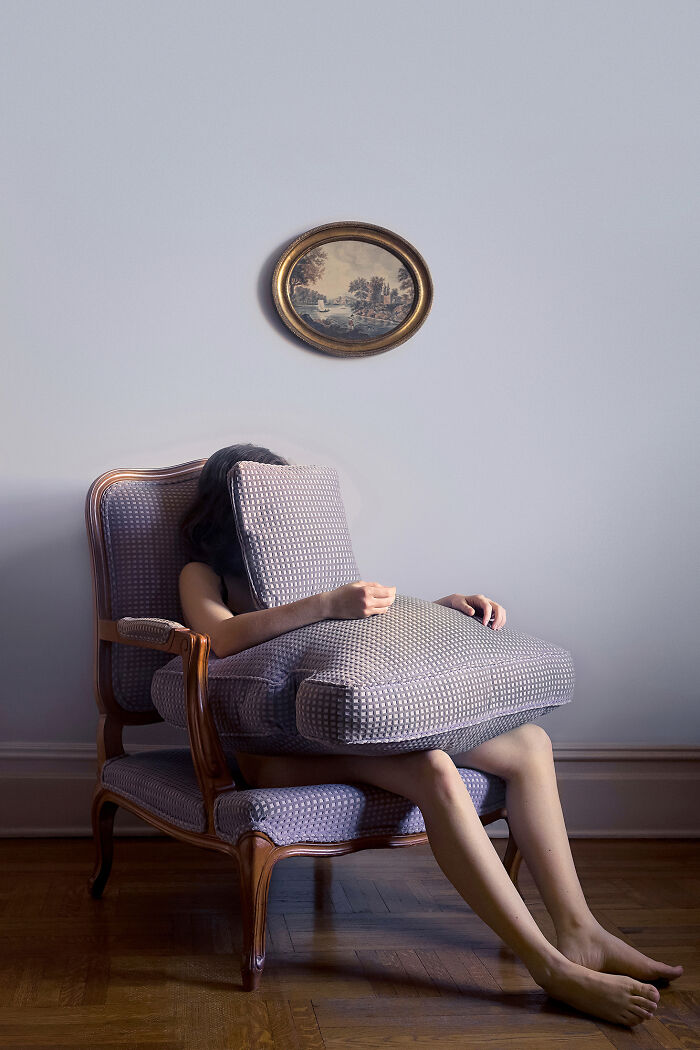 A photographer creates surreal images; a person sits in an armchair, their face obscured by a large cushion.