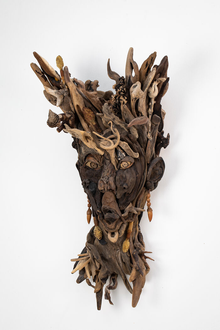 An artistic sculpture of a face crafted from collected pieces of wood, showcasing unique forms and organic elements.