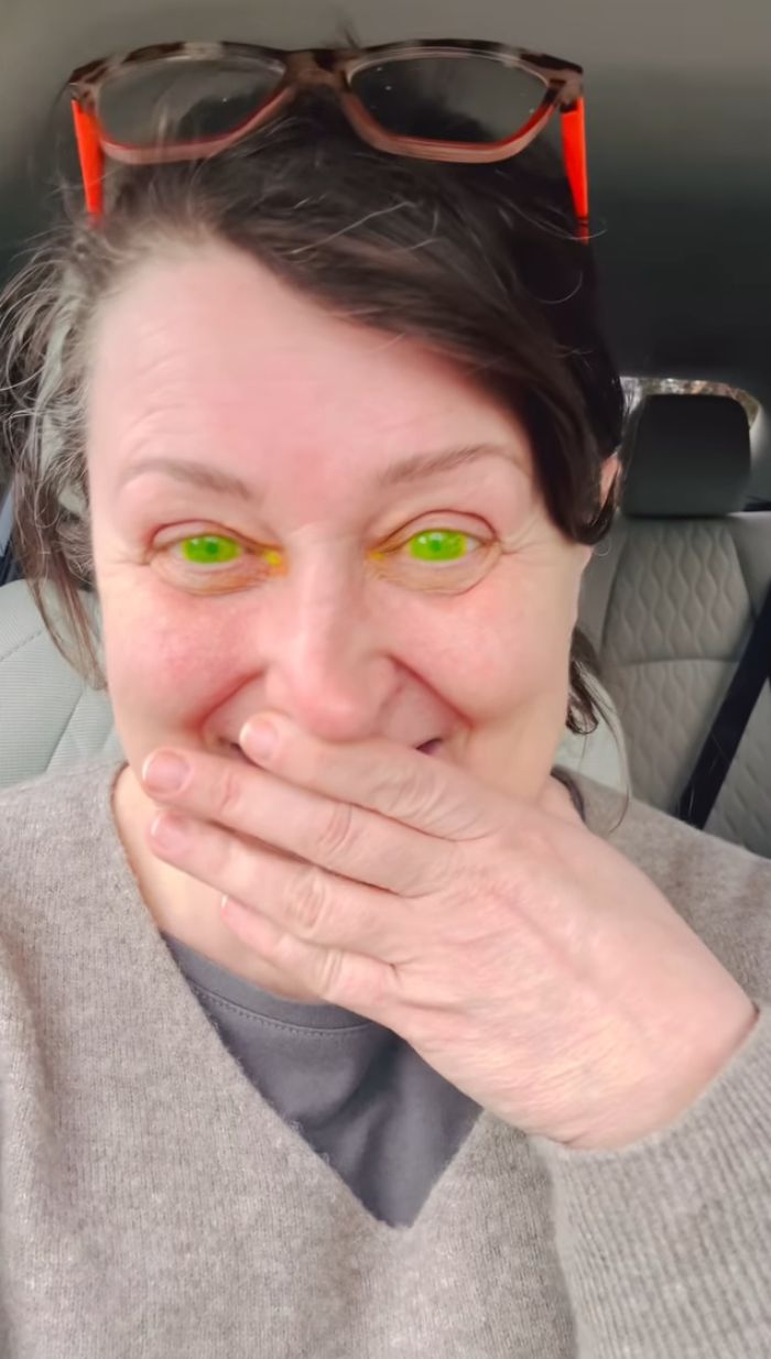 Woman laughing with fluorescent green pupils covering her mouth. Woman laughing with fluorescent green pupils covering her mouth.