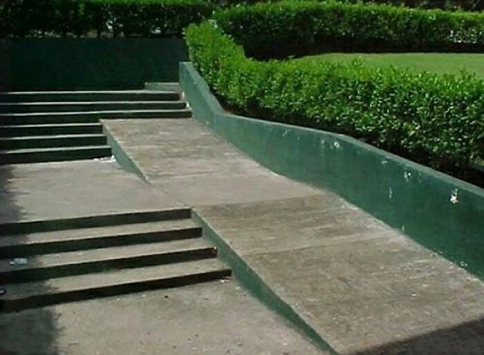 A concrete ramp ends abruptly with a step, next to a set of stairs, a failure by urban designers regarding accessibility.