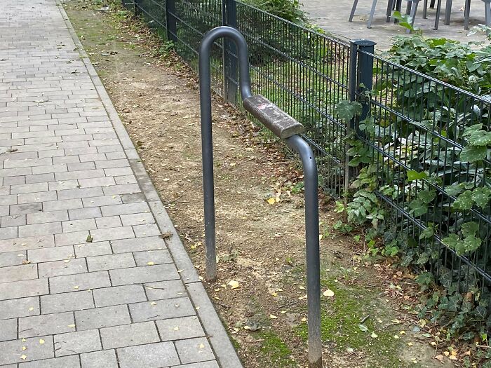 A poorly designed metal bench with minimal seating, showcasing urban designers' oversight in public comfort.