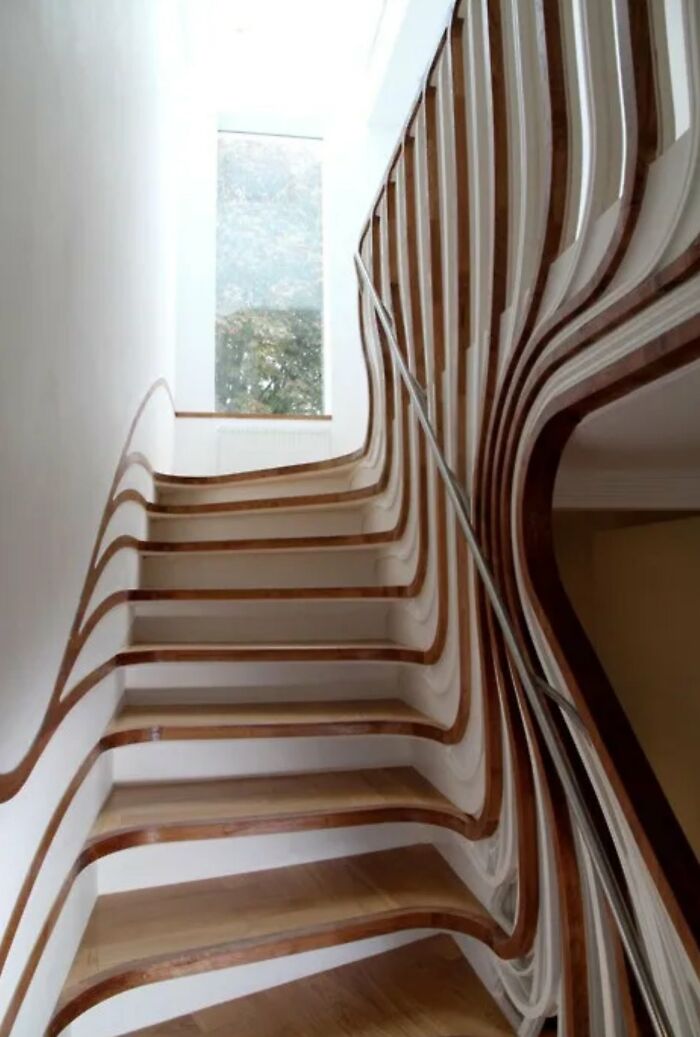 A curved, complex wooden staircase with abstract railings, demonstrating creative yet potentially impractical urban designers work.