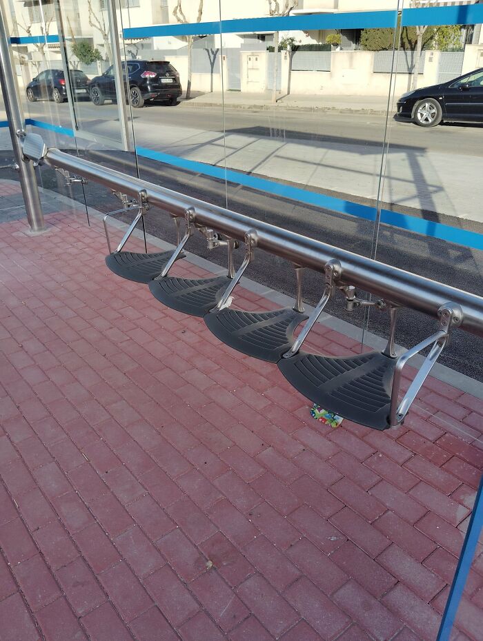 A bus stop with uncomfortable, small individual seats, highlighting urban designers lack of comfort for people.