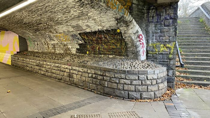 An underpass with anti-homeless spikes on ledges, illustrating urban designers failed to consider people's happiness.