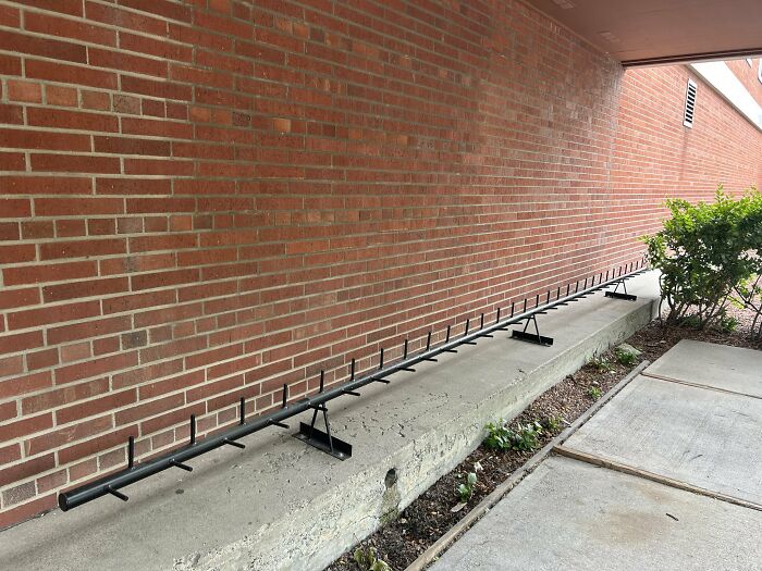A long metal bar with spikes, a clear instance of urban design ignoring people's comfort.