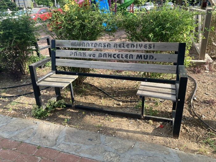An old park bench with two small, uncomfortable seats, demonstrating urban designers neglecting people's comfort.
