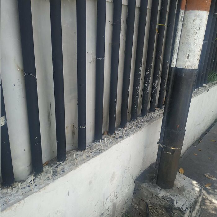 A fence with sharp spikes on top, installed by urban designers to deter people, showcasing a lack of comfort.