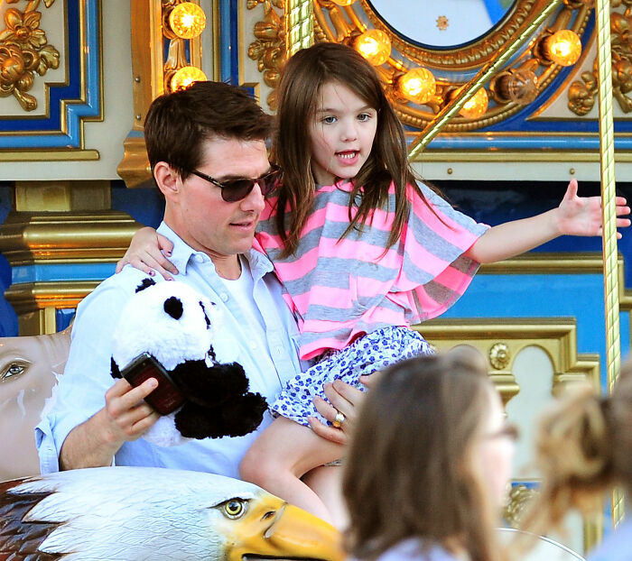 Tom Cruise and Suri on a carousel, highlighting Suri's legal action in a blunt move against her father.