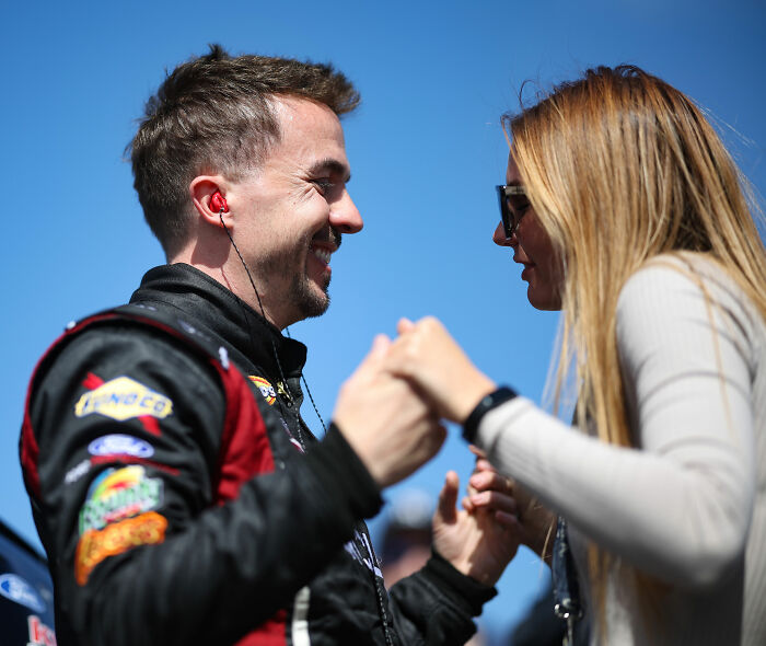 Malcolm In The Middle star Frankie Muniz holding hands with wife Paige, smiling at each other.