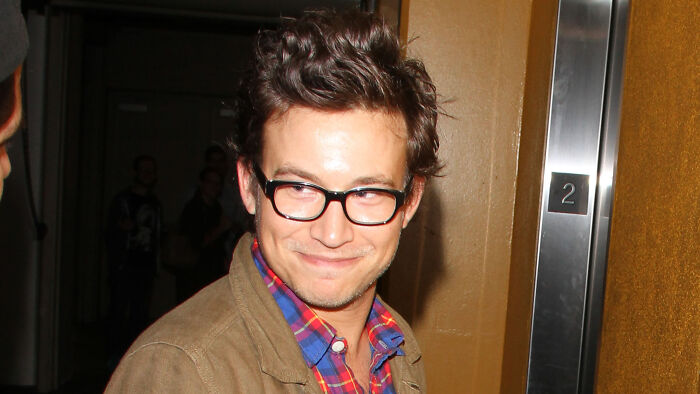 A 90s child star poses for a photo after a disappointing reboot update, wearing glasses and a brown jacket. A 90s child star poses for a photo after a disappointing reboot update, wearing glasses and a brown jacket.