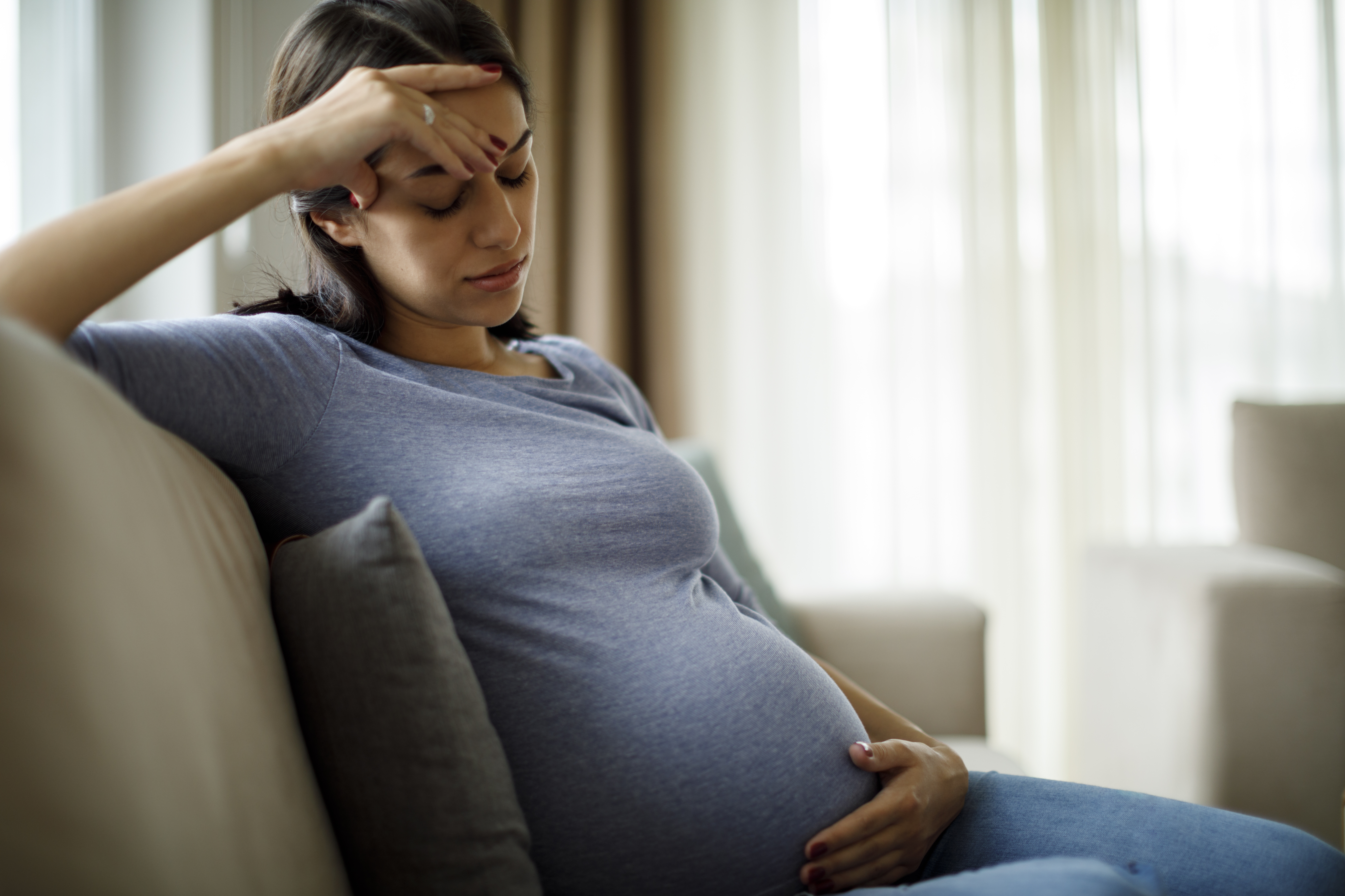 A pregnant woman, about to give birth, looks upset on a couch as her boyfriend delivers a nasty surprise. A pregnant woman, about to give birth, looks upset on a couch as her boyfriend delivers a nasty surprise.