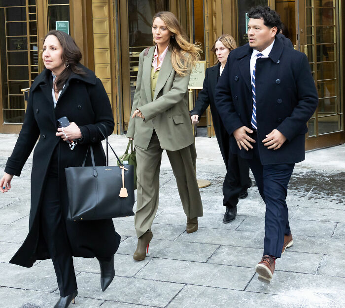 Blake Lively leaving a building, with rumors of Ryan Reynolds facing Hollywood backlash.