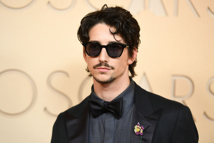 A man with dark hair, sunglasses, and a suit, hinting at the divide over the live-action Disney Princess remake. A man with dark hair, sunglasses, and a suit, hinting at the divide over the live-action Disney Princess remake.