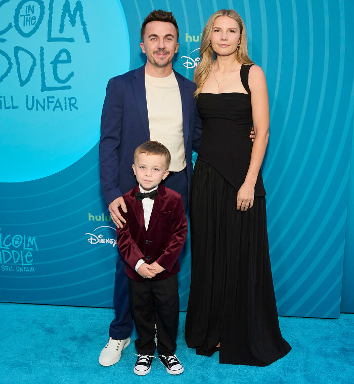 Malcolm In The Middle star and wife Paige with their child on a blue carpet at an event. Family portrait.