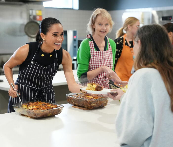 Meghan Markle, wearing an apron, serves food to people in a kitchen, amidst ongoing allegations of lies about her upbringing. Meghan Markle, wearing an apron, serves food to people in a kitchen, amidst ongoing allegations of lies about her upbringing.