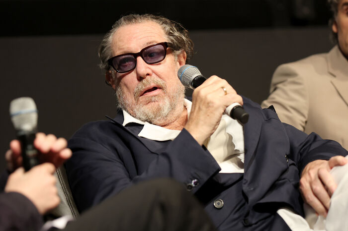 A man with glasses and a beard speaking into a microphone at an event.