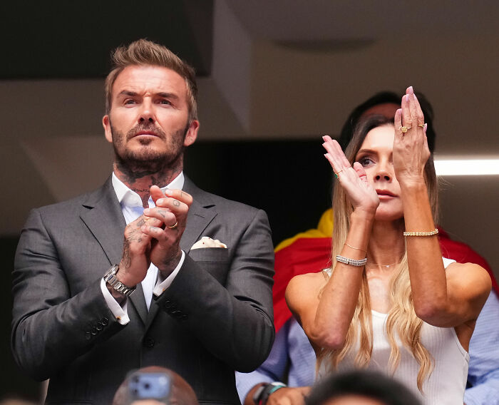 Victoria Beckham and David Beckham clapping, showing their behavior at an event. Victoria Beckham and David Beckham clapping, showing their behavior at an event.