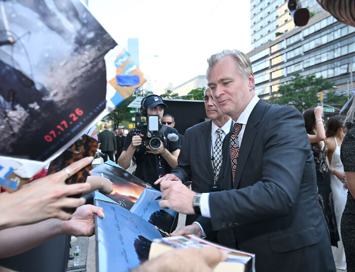 Christopher Nolan signing autographs for fans outdoors. Christopher Nolan's bizarre rules spark backlash after items banned. Christopher Nolan signing autographs for fans outdoors. Christopher Nolan's bizarre rules spark backlash after items banned.