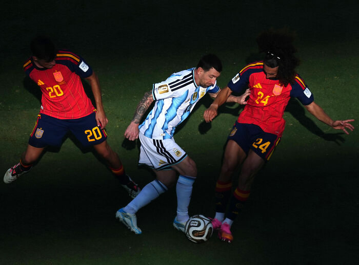 Lionel Messi in an intense World Cup Final match, surrounded by two opposing players. Lionel Messi in an intense World Cup Final match, surrounded by two opposing players.