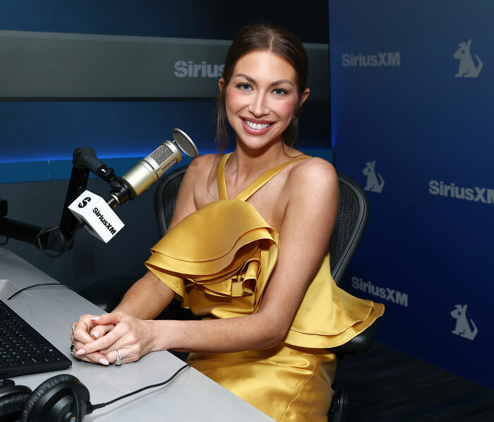 Stassi Schroeder smiles in a gold dress at SiriusXM, discussing SpongeBob comparisons after her SI Swimsuit Runway.