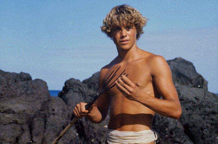 Young actor from Blue Lagoon holding spear near rocks Young actor from Blue Lagoon holding spear near rocks