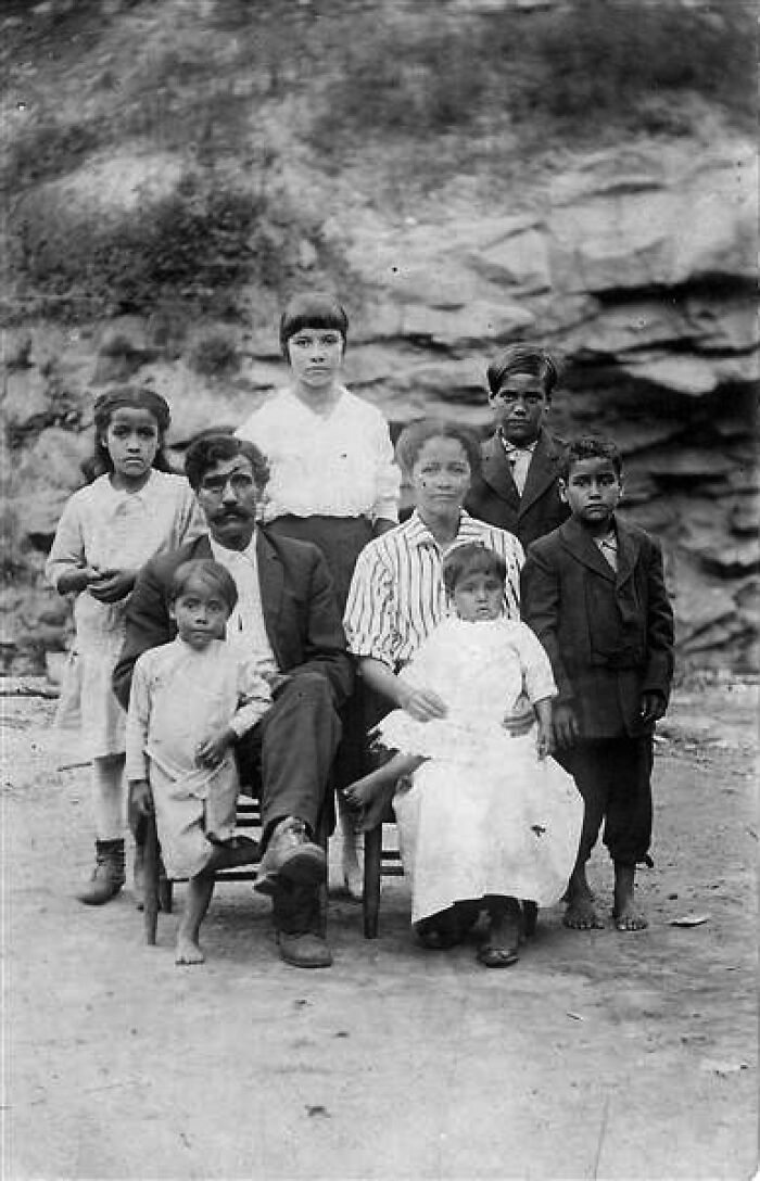 A black and white photograph of a family, posing in front of a rocky background, among unsolved mysteries.