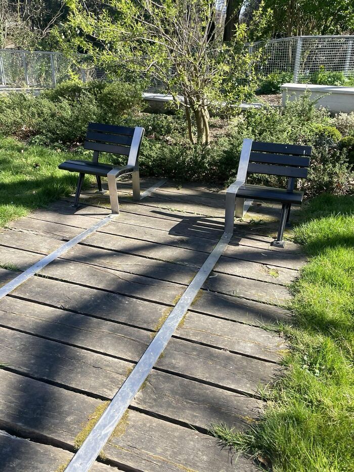 Two benches installed facing opposite directions with a long metal strip, highlighting urban designers design flaws.