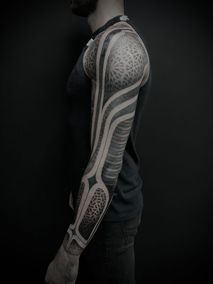 A professional tattoo artist's work: a full sleeve geometric and abstract tattoo design on a man's arm.