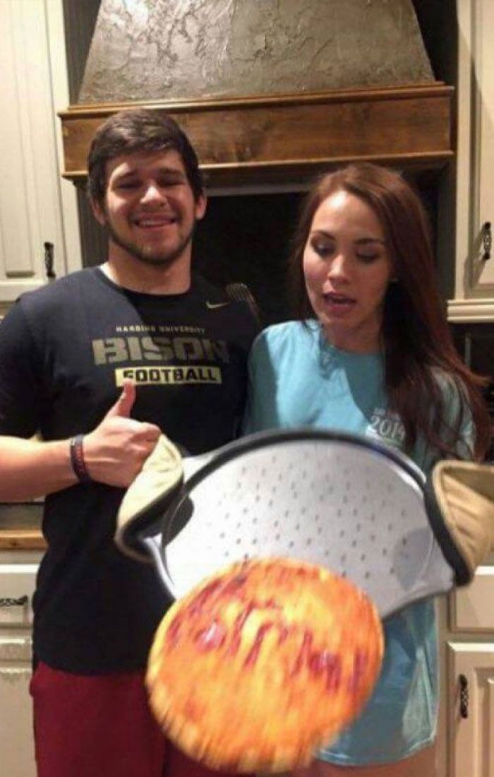 Hilarious photo of a couple in a kitchen, pizza moments before disaster.