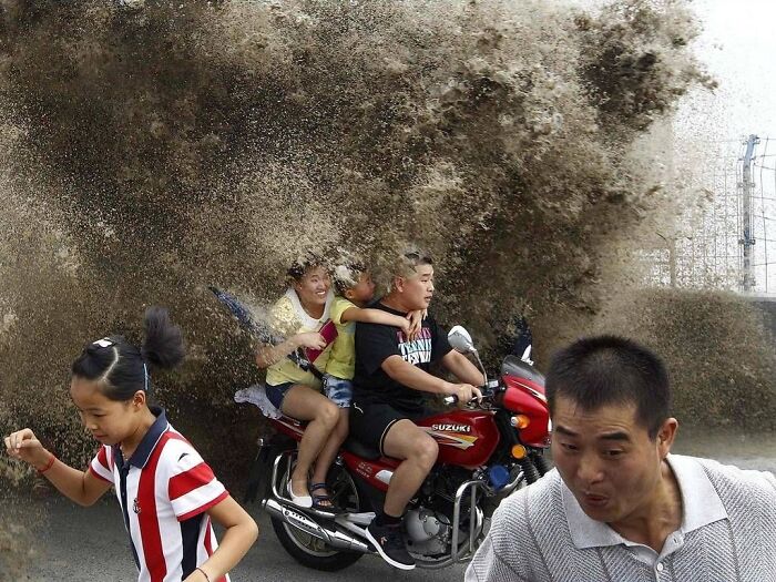 A family on a motorcycle looks back at a massive splash, a hilarious photo taken moments before disaster.